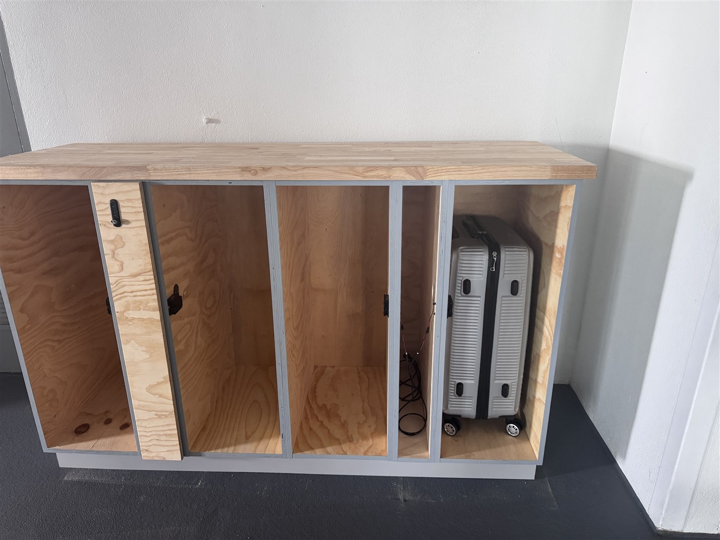 Open locker cabinet showing a large checked suitcase inside