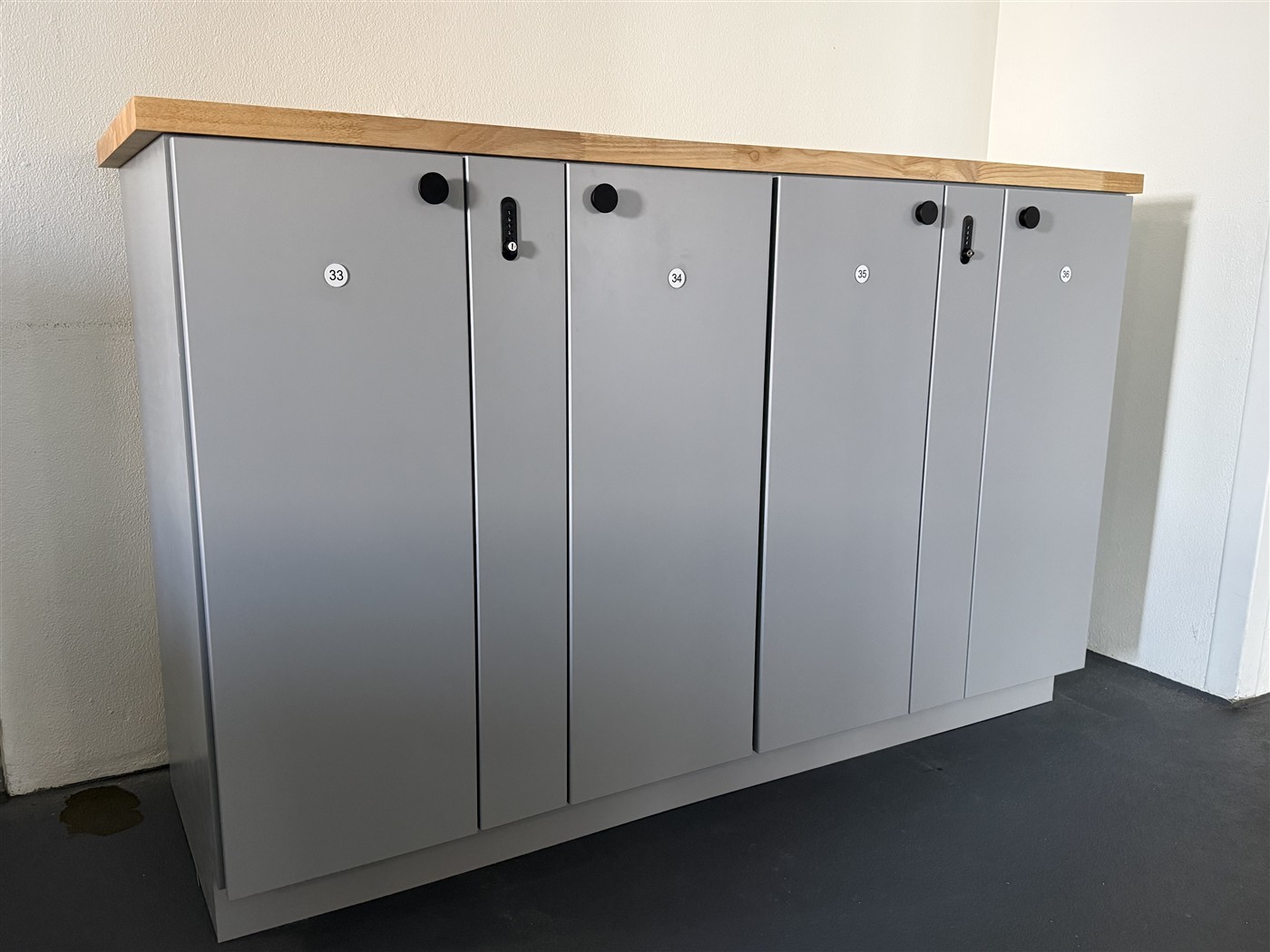 Installed luggage locker cabinet with gray doors and a wood countertop